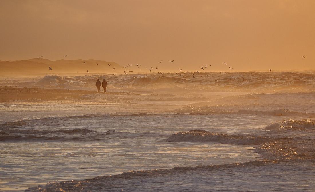 Couple walking on a beach at sunset